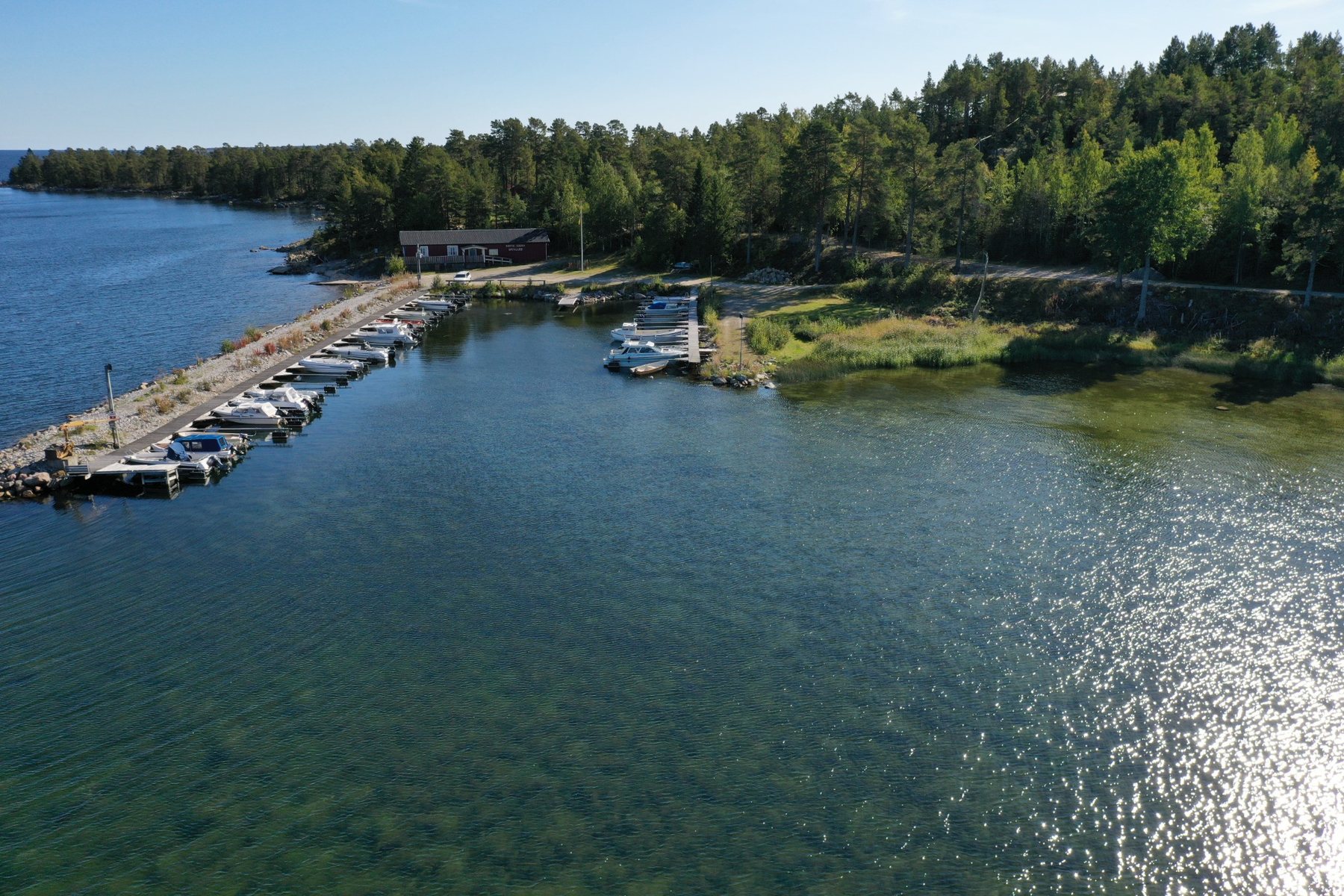 Vy över hamnen i Hårte med båtplatser, vatten och skog